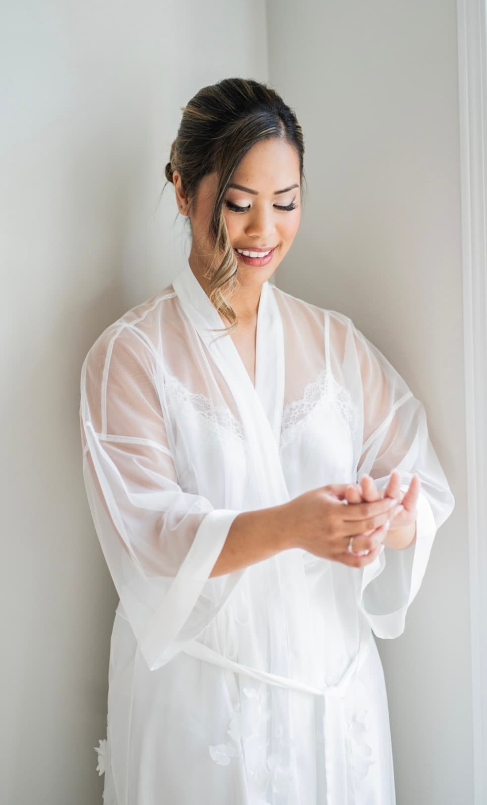 Bride in white robe with soft intimate bridal makeup