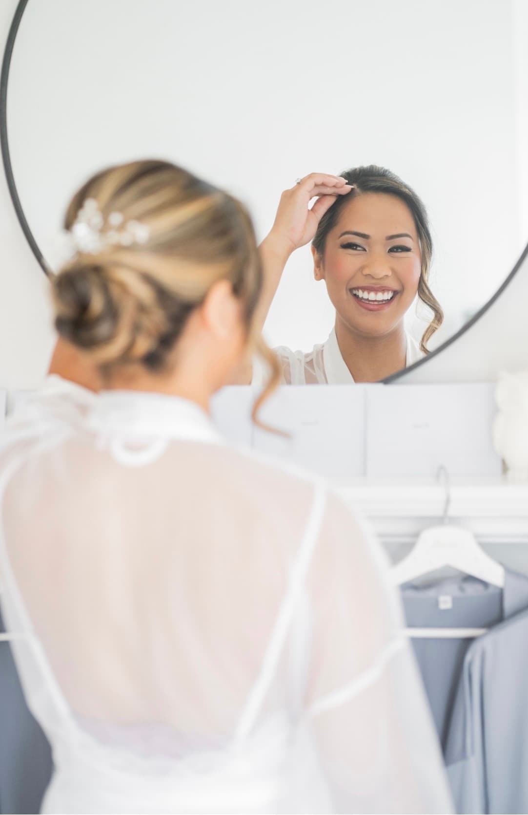 Bride smiling at her reflection in the mirror on wedding morning